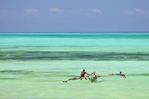 Bright Gallery: Tanzania, Zanzibar, Unguja, Jambiani. A man sits on his boat near the shore