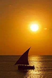 Images Dated 7th March 2012: Tanzania, Zanzibar, Unguja, Stone Town. A Dhow sails out of the harbour at sunset