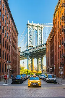 Taxi passing under the Manhattan bridge with the Empire state building framed in