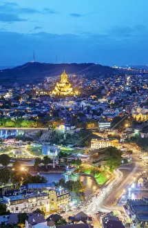 Orthodox Church Prints: Tbilisi and the Mtkvari river at dusk. On the top the Holy Trinity Cathedral (Tsminda