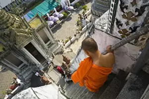 Land Mark Prints: Thailand, Bangkok. A monk descends the steps of the prang (Khmer-style tower) at Wat Arun