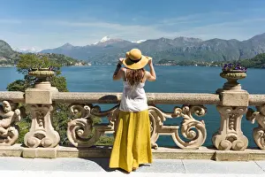 Tourist admiring Como lake view from the balcony of villa del Balbianello on punta