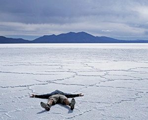 Salar De Uyuni Gallery: A tourist lies on the salt crust of the Salar de Uyuni
