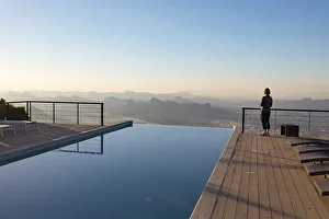 A tourist looks out at the view from the swimming pool at The View hotel, Al Hamra, Oman