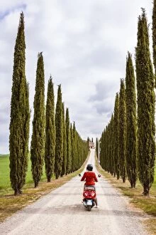 Tourist riding an italian vespa motorcycle in the countryside. Val d'Orcia, Tuscany