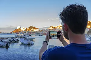 Pastel Prints: Tourist taking picture with his smartphone at the colourful mediterranean village of Ponza