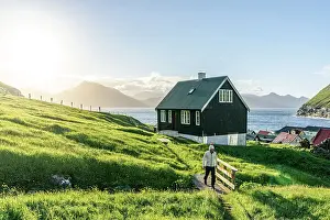 Enjoyment Prints: Tourist walking in the green landscape surrounding the coastal village of Gjogv