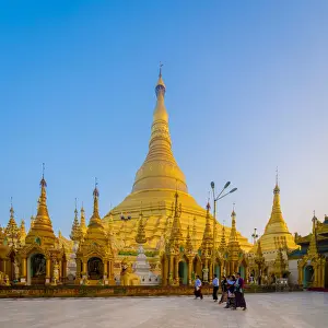 Tourists at gilded Shwedagon Pagoda against clear sky at sunrise, Yangon, Yangon Region