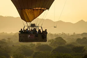 Tourists in a hot air balloon basket flying over vegetation, UNESCO, Bagan, Myanmar Tourists in a hot air balloon basket flying over vegetation, UNESCO, Bagan, Myanmar