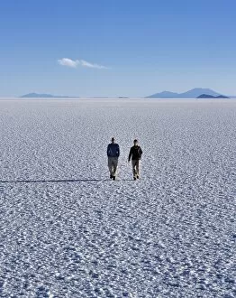 Salar De Uyuni Gallery: Two tourists walk across the endless salt crust of the Salar de Uyuni