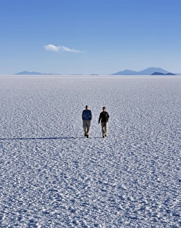 Salar De Uyuni Gallery: Two tourists walk across the endless salt crust of the Salar de Uyuni