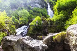 A tourit walks on a Tibetan bridge near the Cascata del Ri da Sernel, Brontallo, Val