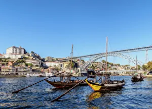 Traditional boats on Vila Nova de Gaia bank of Douro River, Dom Luis I Bridge in