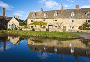Traditional Cotswold cottages and a water mill reflected in the river Eye, Lower Slaughter