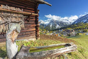 Traditional fountain with view on the alpine village. Arosa, Canton of Graubunden
