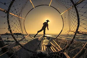 Images Dated 23rd April 2020: Traditional leg-rowing fisherman viewed through conical fishing net rowing a boat on Lake