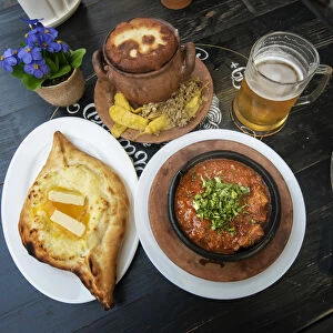 Images Dated 30th July 2018: Traditional Lobio (stewed beans) in a ceramic pot and Adjaruli Khachapuri
