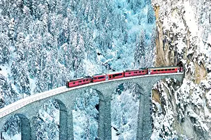 Railway Track Prints: Train on Landwasser viaduct entering in a tunnel carved into a mountain ridge in winter