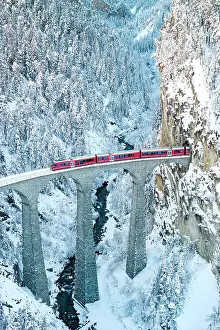 Railway Track Prints: Train on Landwasser viaduct entering in a tunnel carved into a snowy mountain ridge