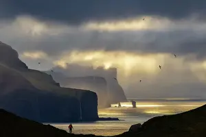 Denmark Prints: A trekker observes the scenic view in front of him from Kallur Lighthouse at sunset