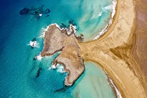 Wave Collection: Turquoise ocean surrounding El Islote rock islet and Cofete Beach from above, Jandia
