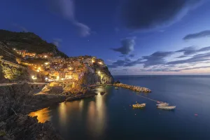 Twilight in Manarola, Cinque Terre, the most beautiful moment of the day when the lights of the town come