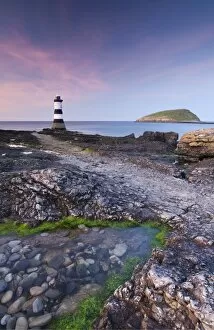 Lighthouses Collection: Twilight on the rocky Anglesey coast looking towards Penmon Point Lighthouse and Puffin Island