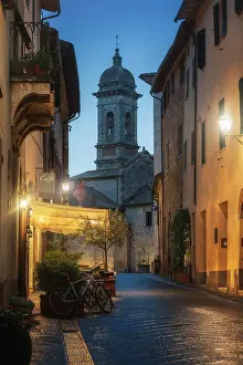 Ancient Building Prints: Twilight street view of San Quirico d'Orcia during a rainy winter evening in Val d'Orcia