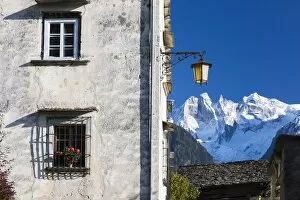 Typical alpine house and street lantern frame the snowy peaks Soglio Bregaglia Valley