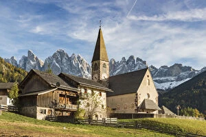 Typical houses and the church of the village with Odle Dolomites peaks on the background