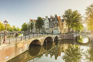 Typical houses reflecting in Keizergracht water canal at sunrise in Amsterdam