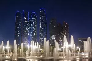 UAE, Abu Dhabi, Emirates Palace Hotel fountains and Etihad Towers, dusk