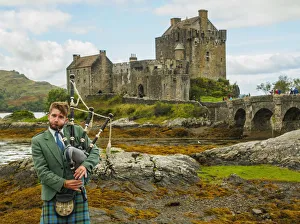 UK, Scotland, Highlands, Dornie, Man in Highland Dress playing bigpipe in front of