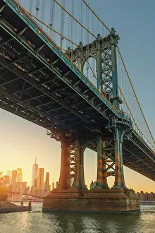 Q4 2023 Prints: USA, New York City, view from below of the Manhattan bridge with the sun setting on lower Manhattan