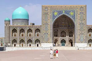 What's New: Uzbekistan, Samarkand, Registan square, tourists admire the facade of the Tilya-Kori Madrasah