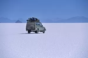 Salar De Uyuni Gallery: A vehicle drives across the crusted salt of the Salar de Uyuni
