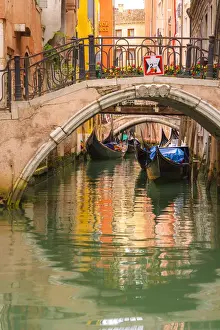 Venice, Veneto, Italy. Bridges and gondolas moored in a canal