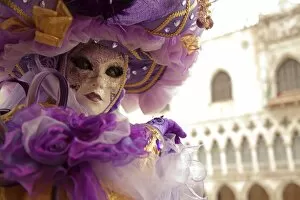 Unesco World Heritage Collection: Venice, Veneto, Italy; A masked character in front of the Palazzo dei Dogi during Carnival