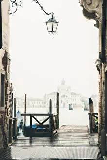 Venice, Veneto, Italy. Pier on the waterfront in the mist and St Mary Of The Presentation