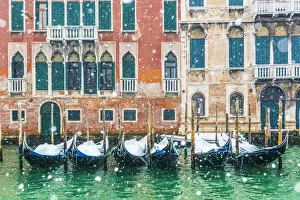 Venice, Veneto, Italy. Snowfall over moored gondolas along the Grand Canal (Canal Grande)