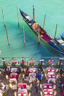 Venice, Veneto, Italy. Tourists eating out on the riverside of the Grand Canal