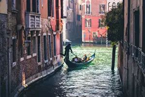 Gondoliers Prints: Venice, Veneto, Italy. Tourists on a gondola in a backstreet canal