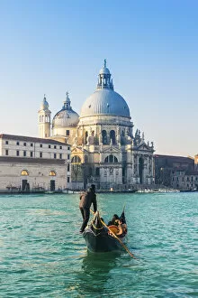 Venice, Veneto, Italy. Tourists on a gondola over the Grand Canal towards the Salute