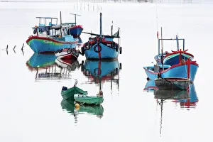 Tradional Prints: Vietnam, Cam Ranh, an egret sits among fishing boats reflected in calm water