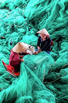 Turqouise Prints: Vietnam, Cam Ranh, two men repair green fishing nets using a sewing machine