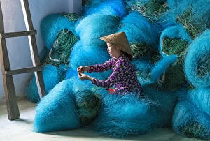 Craft Gallery: A Vietnamese woman mending blue fishing net, Mekong Delta, Vietnam