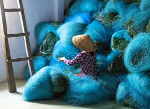 A Vietnamese woman mending blue fishing net, Mekong Delta, Vietnam