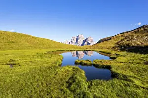 Mirror Lake Prints: View of green meadows and hills by the lake of Baste reflecting the shape of mount Pelmo