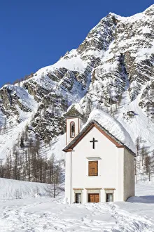 Footprints Prints: View of the mountain church of the small town of Crampiolo in winter