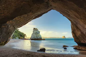 View of a sea stack through a cove at sunset at Cathedral Cove, Coromandel, New Zealand